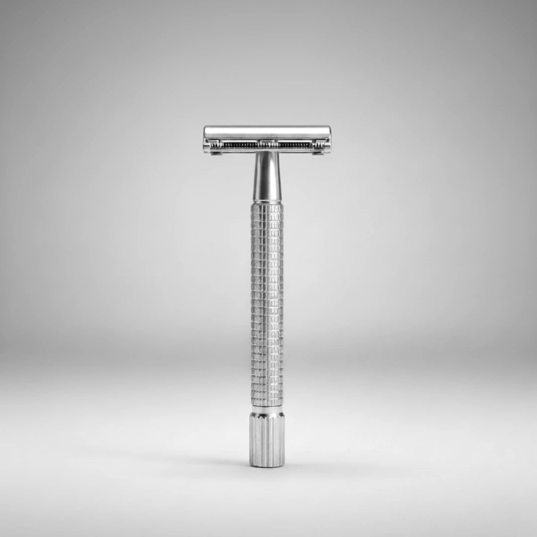 Rasoir de sûreté traditionnel à ouverture papillon chrome. Posé verticalement sur un fond gris épuré. Idéal pour un rasage traditionnel élégant.