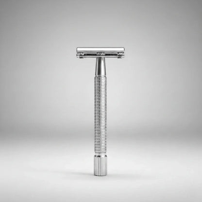 Rasoir de sûreté traditionnel à ouverture papillon chrome. Posé verticalement sur un fond gris épuré. Idéal pour un rasage traditionnel élégant.