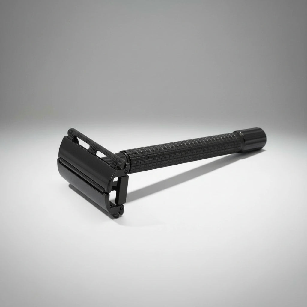 Gros plan sur la tête d'un rasoir de sûreté à ouverture papillon noir. Manche travaillé pour une prise en main antidérapante.