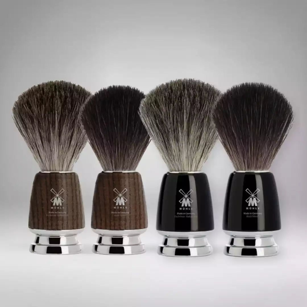 Présentation de la collection complète de blaireaux de rasage Mühle. Un choix d'excellence entre manches en bois de frêne et résine noire précieuse, avec poils de blaireau (Pure Badger) ou fibres synthétiques (Black Fibre).